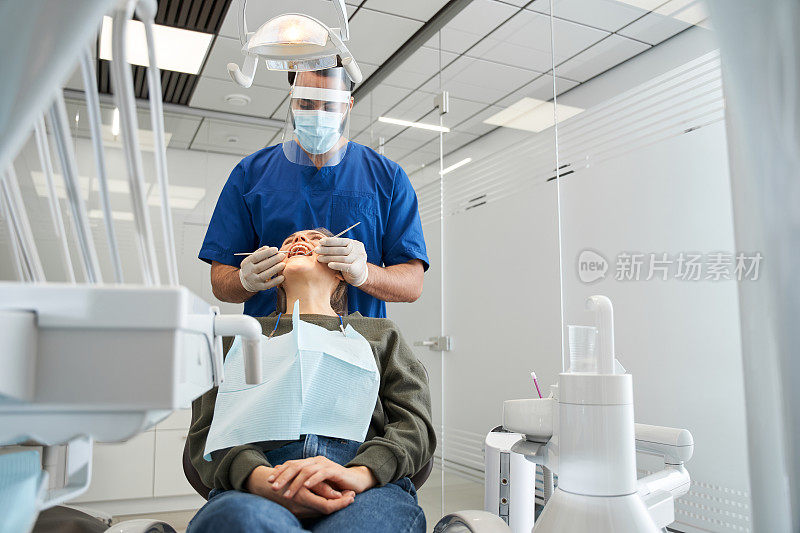 牙医检查他的金发女客户的牙齿