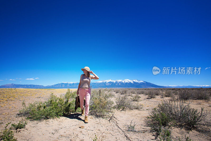 独自行走在沙漠中的女人，雪山背景