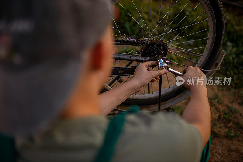 一个十几岁的男孩，正在修理自行车的坏轮胎