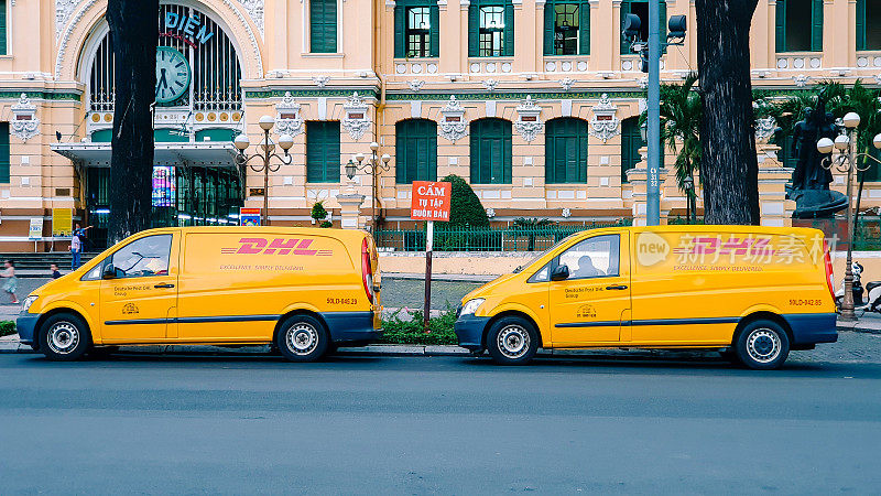两辆DHL快递车停在越南胡志明市中心的街道上