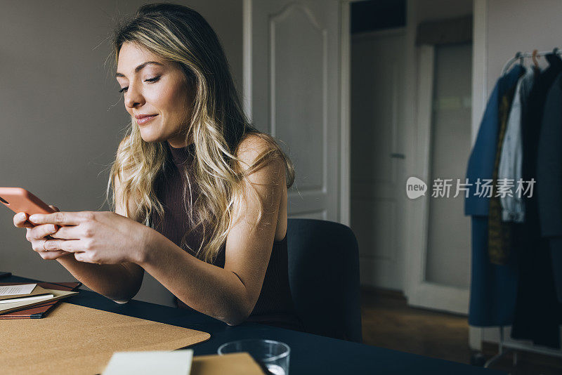 新常态概念-在家工作时休息一下:年轻美丽微笑的白人女性在智能手机上发短信(横向)