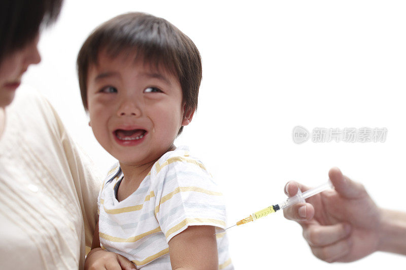母亲抱着哭泣的男婴，他正在接种疫苗