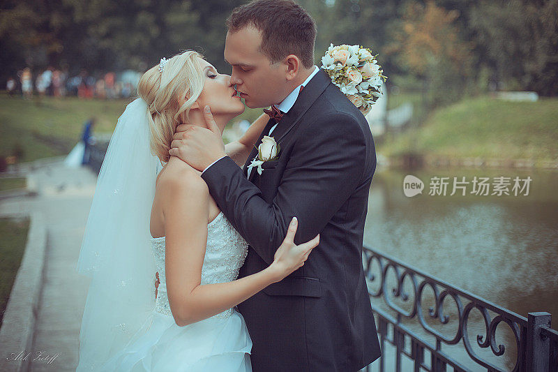新郎在湖的背景上温柔地亲吻新娘