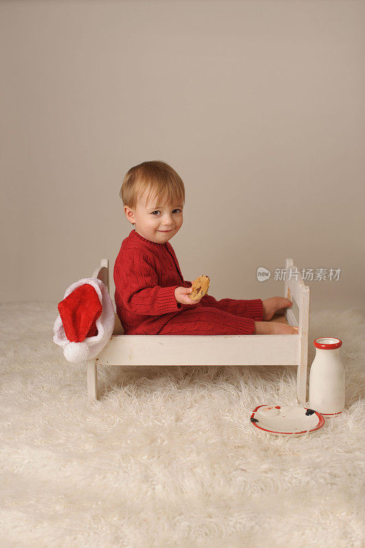 微笑的小男孩坐在木床上拿着饼干