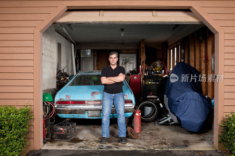 一个男人站在杂乱肮脏的车库里