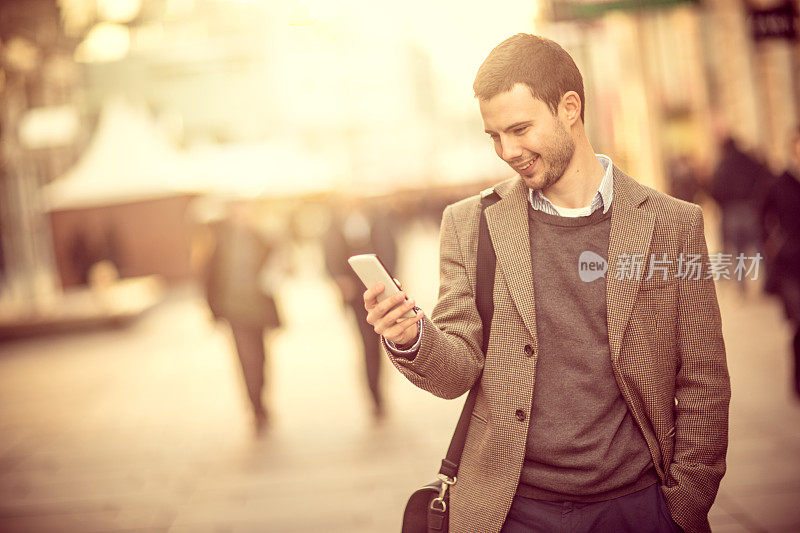 在街上用智能手机微笑的男人