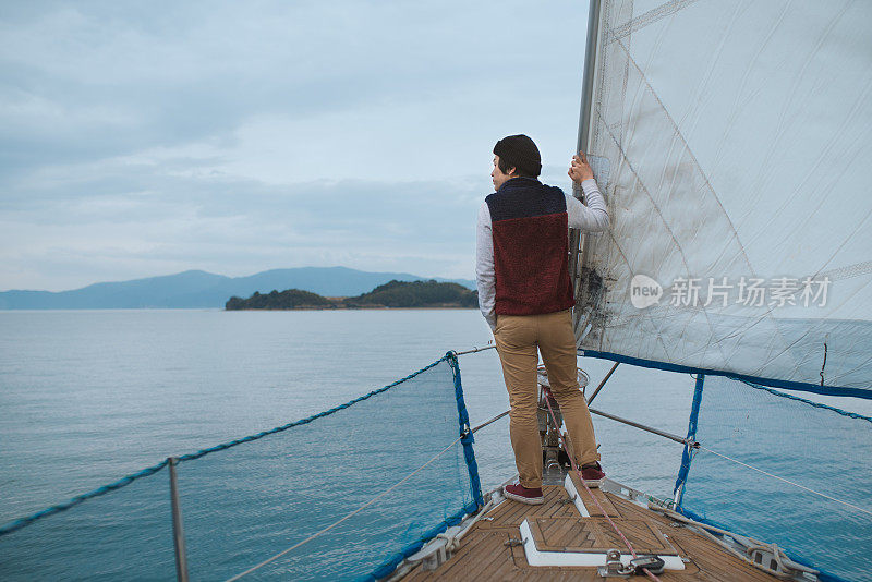年轻人站在一艘豪华游艇的船头