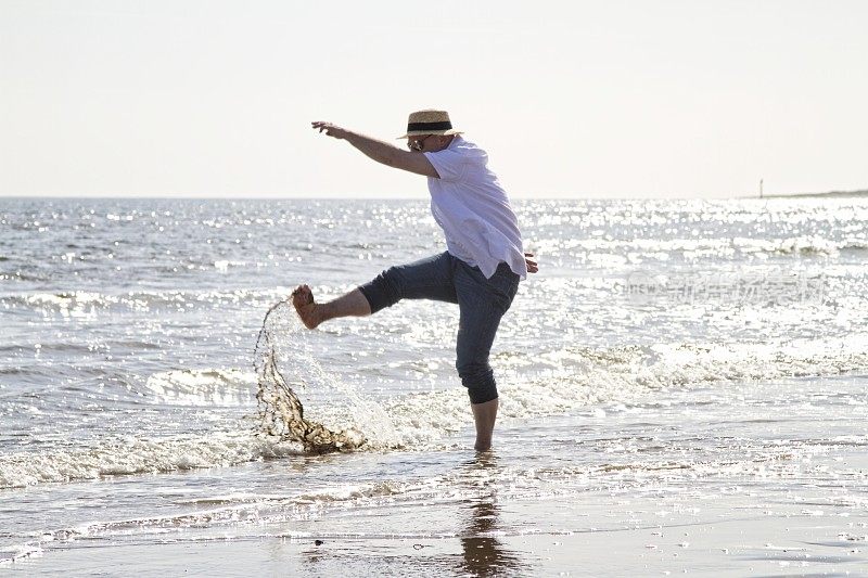 一个成熟的男人在海滩上泼水