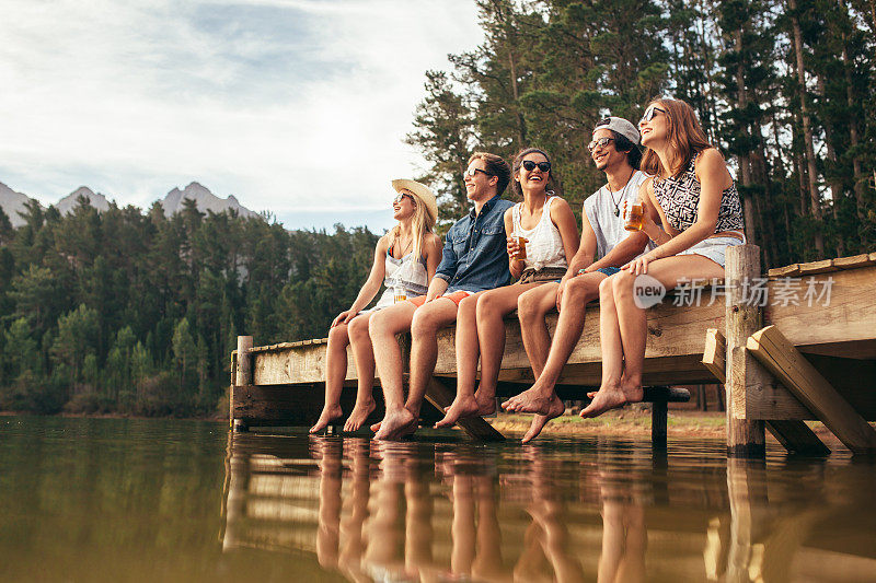 一群朋友坐在湖边的码头上