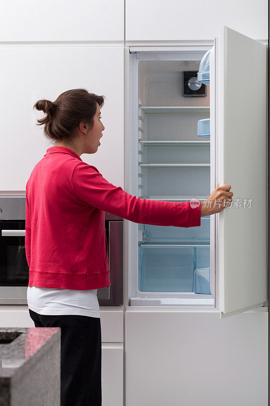 惊恐的女人对着空冰箱