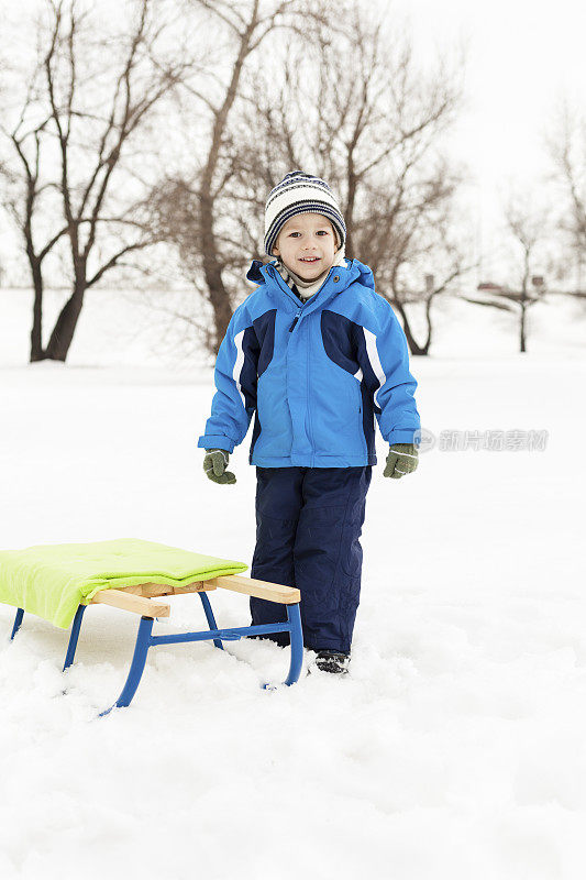 带着雪橇的小男孩在户外