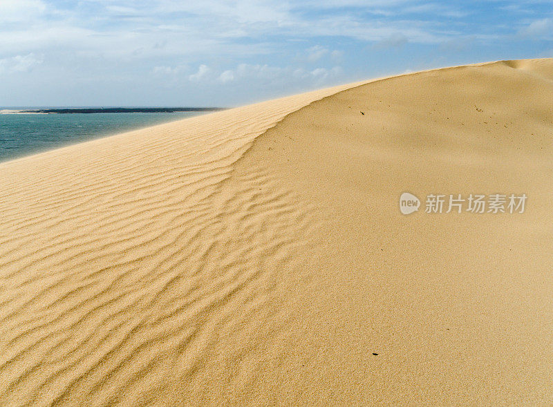 蓝天下靠近海水的沙丘