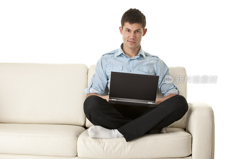 一个年轻人在沙发上拿着笔记本电脑