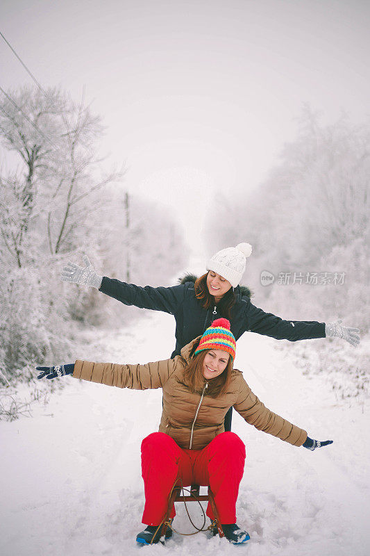 两个可爱的女孩骑着雪橇，玩得很开心