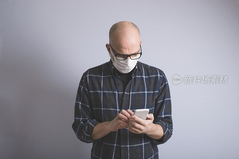 用智能手机戴着空气污染面罩的男子