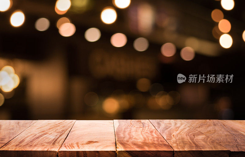 木质桌子与模糊的灯光在晚上的咖啡馆，餐厅背景