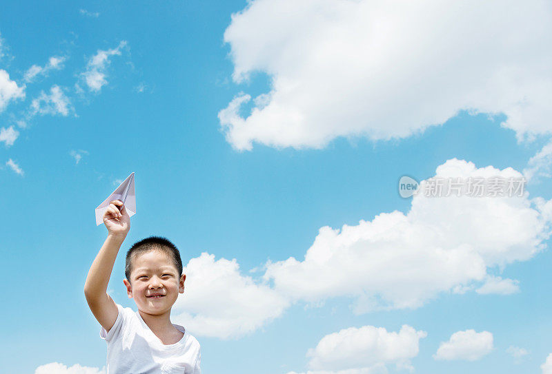 小男孩在田野里玩纸飞机