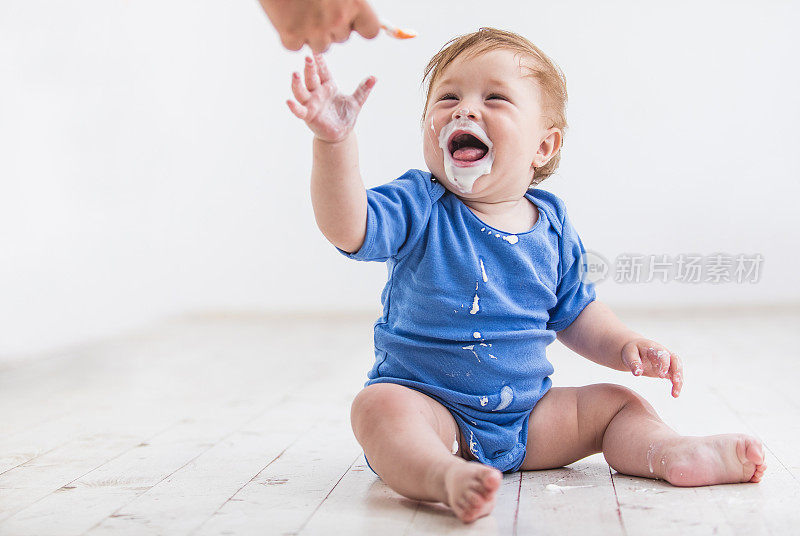 一个面目全非的人拿着勺子给一个男婴喝酸奶