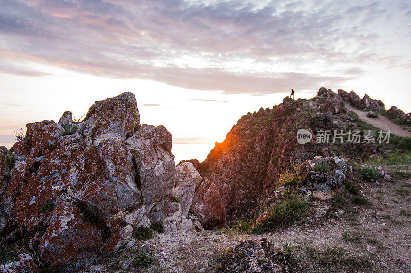 清晨的夕阳环绕着橙色和玫瑰色的岩石和奥尔孔岛和贝加尔湖的山脉