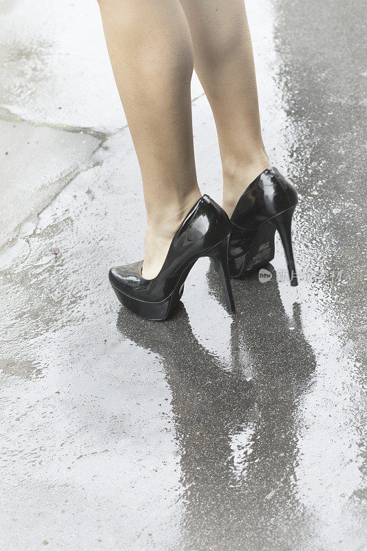 黑色高跟鞋在潮湿的路面上反射