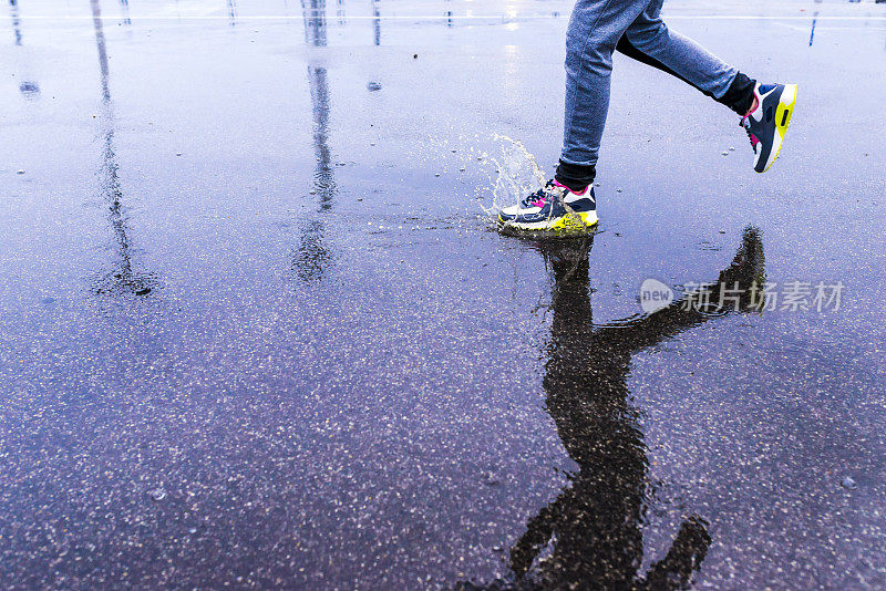 在雨天，年轻女子在沥青操场上跑步