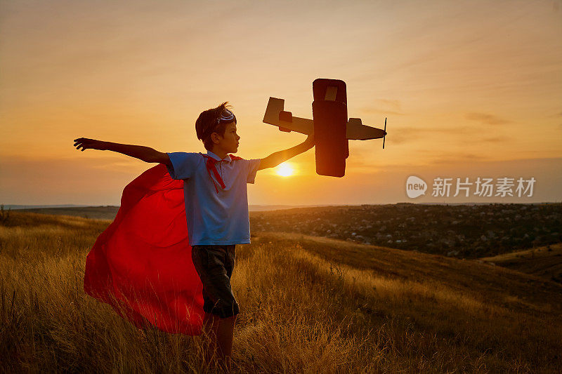 一个穿着超级英雄服装的快乐男孩正在玩一架飞机。