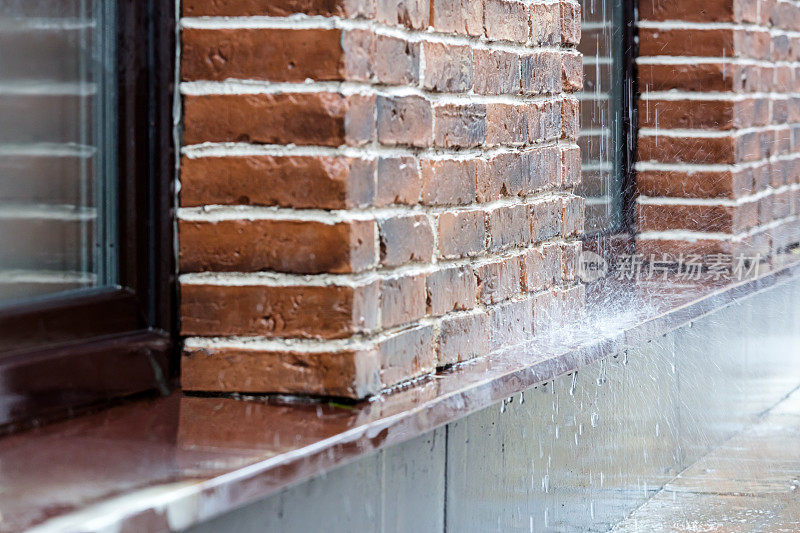 大雨倾泻在砖墙背景的路面上