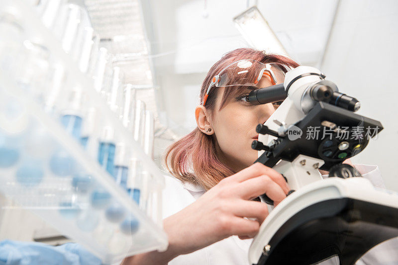 穿着实验服在实验室里透过显微镜看的科学家肖像