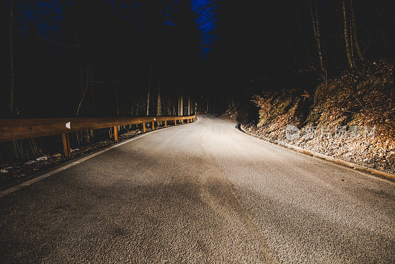 一辆汽车在夜间山路上的前灯-行车安全概念