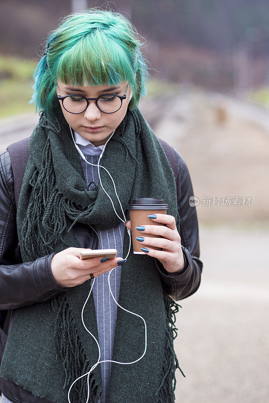 时髦女孩在火车站用智能手机发短信