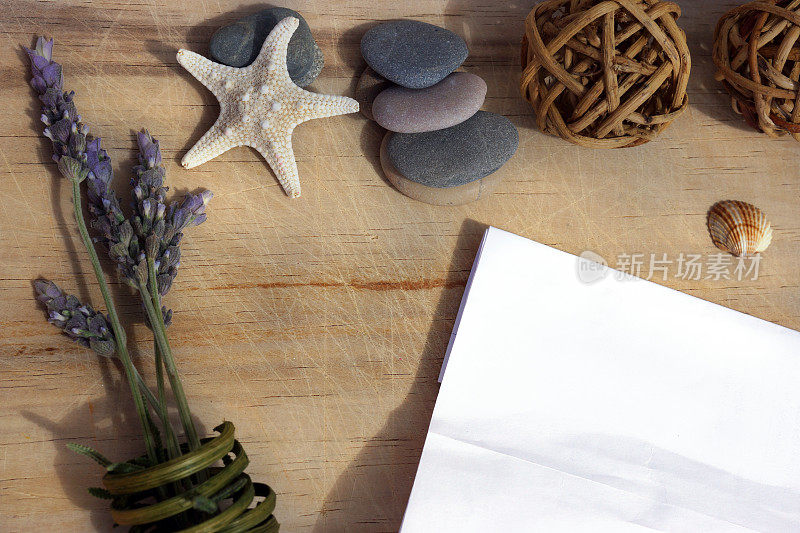 一张白纸躺在一张木桌上，旁边是海石、海星和薰衣草小枝