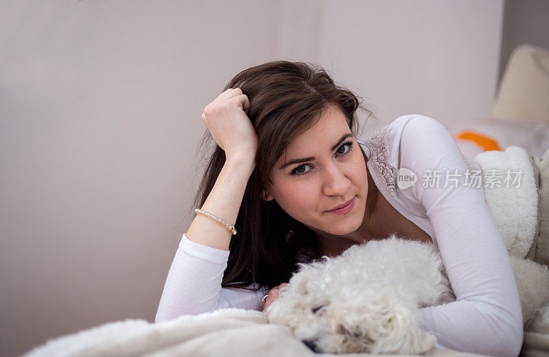一个年轻女人和她的狗在床上。