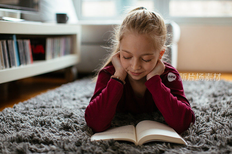 美丽的年轻女孩在家里看书