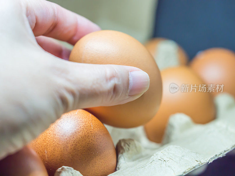 手从纸盘里捡鸡蛋的特写。
