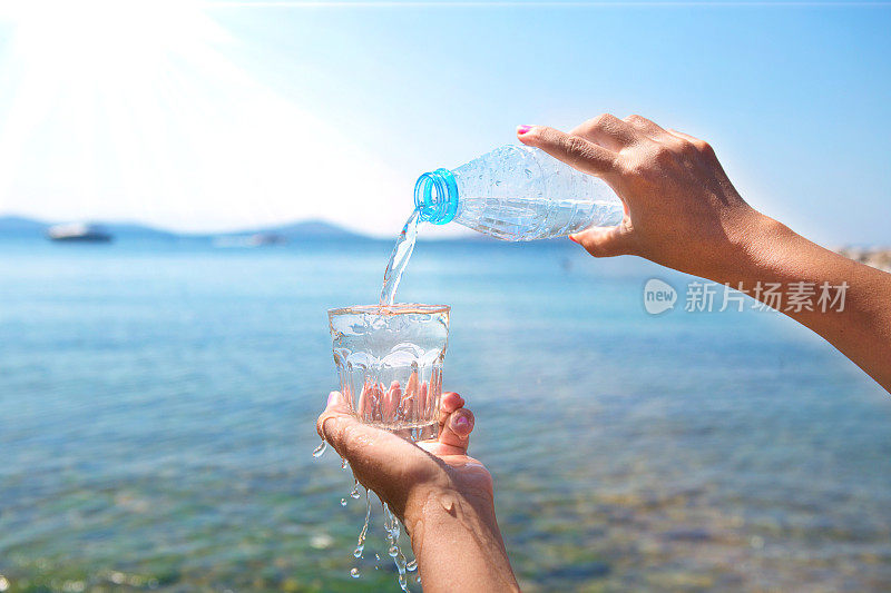 那只手正在把瓶子里的水倒在海滩上。