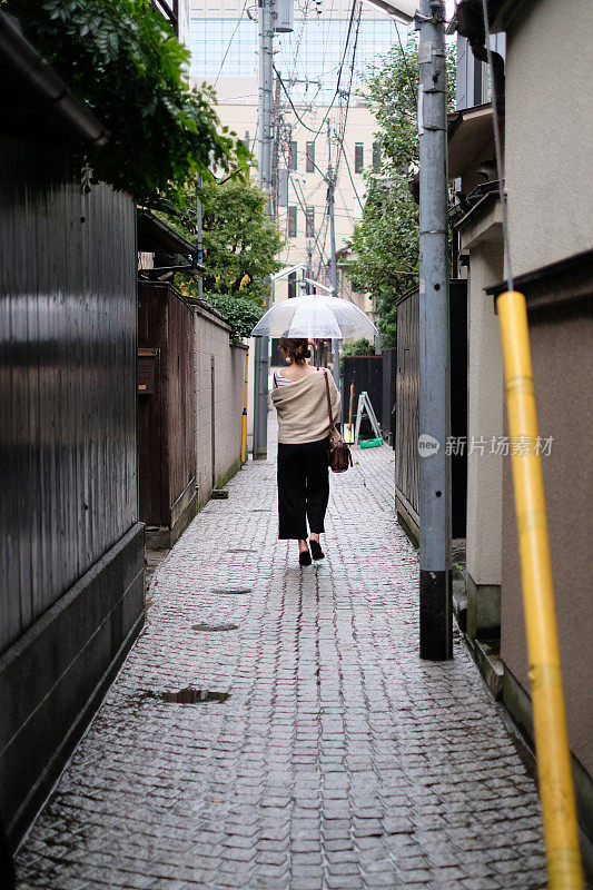 在一个雨天，在东京神乐坂传统老城的小巷里走着的女人的背影