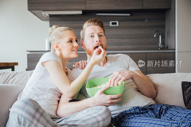 年轻夫妇在家里吃爆米花