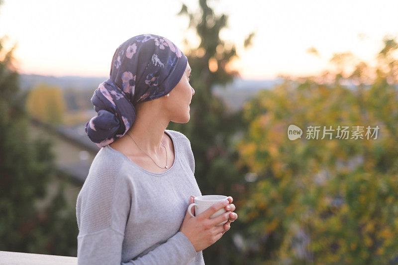 一位与癌症作斗争的妇女站在外面，望着群山