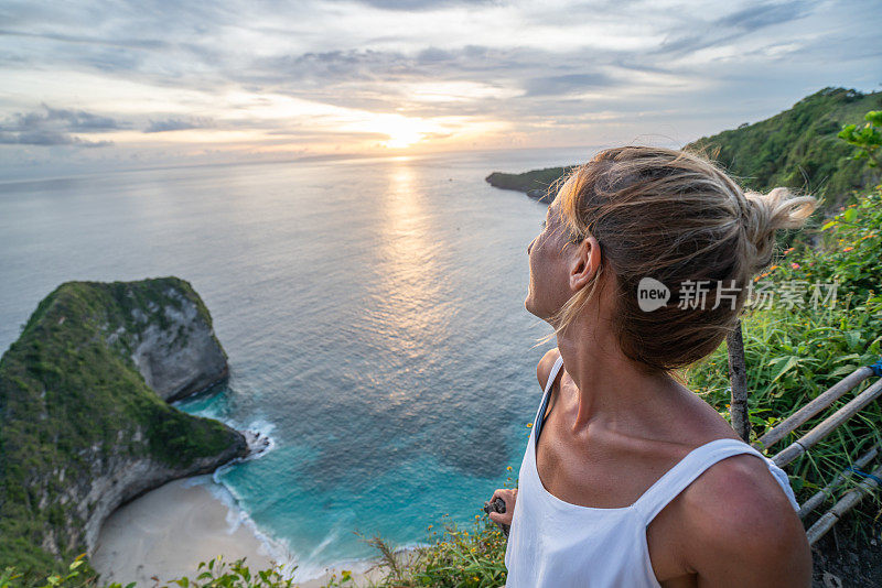 年轻女子俯瞰克林金海滩——蓝色和绿色的沙子，美丽的山在海上形成。旅游目的地度假，人们好奇的概念自然风景