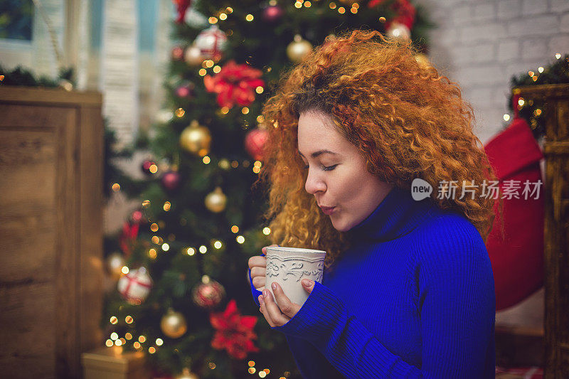 年轻漂亮的女士在温馨的圣诞气氛中喝茶