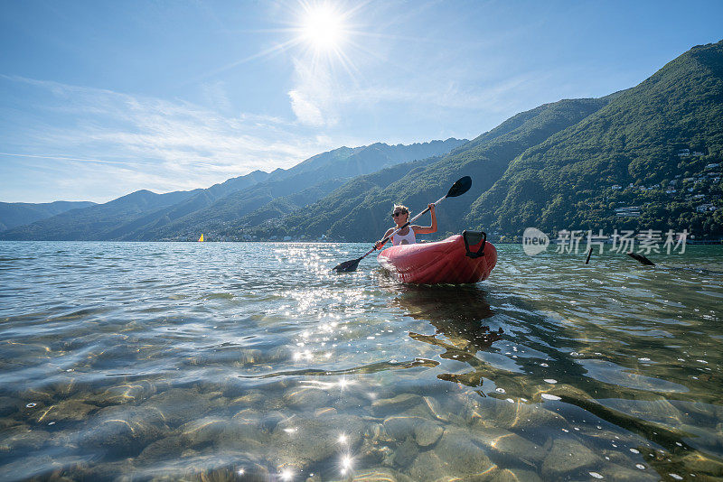 快乐的女性享受独木舟在美丽的湖在瑞士