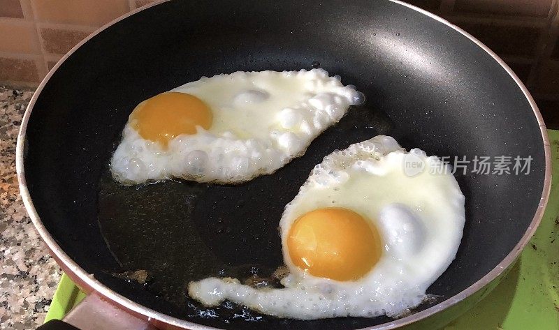 在不粘锅里用油煎蛋的形象