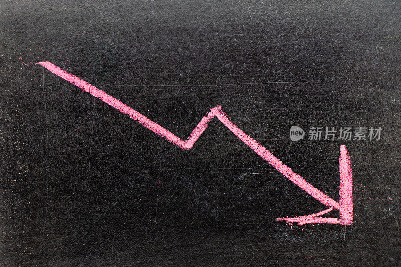 红色手绘粉笔在黑色的黑板背景上以箭头向下的形状(股票下跌的概念，业务下降的趋势，经济)