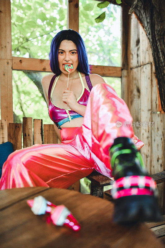 奇特的吉普赛女性在彩色服装吃棒棒糖，而坐在木棚里
