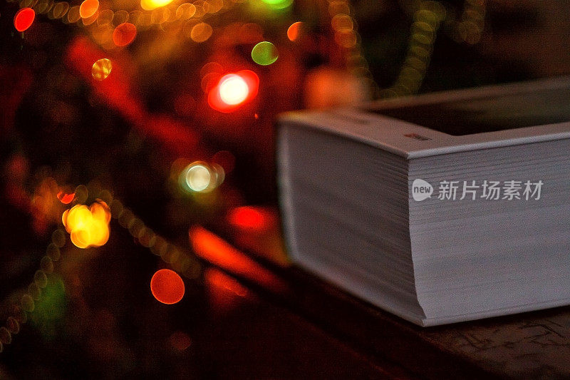 厚厚的书放在圣诞树的背景上，挂着圣诞彩灯