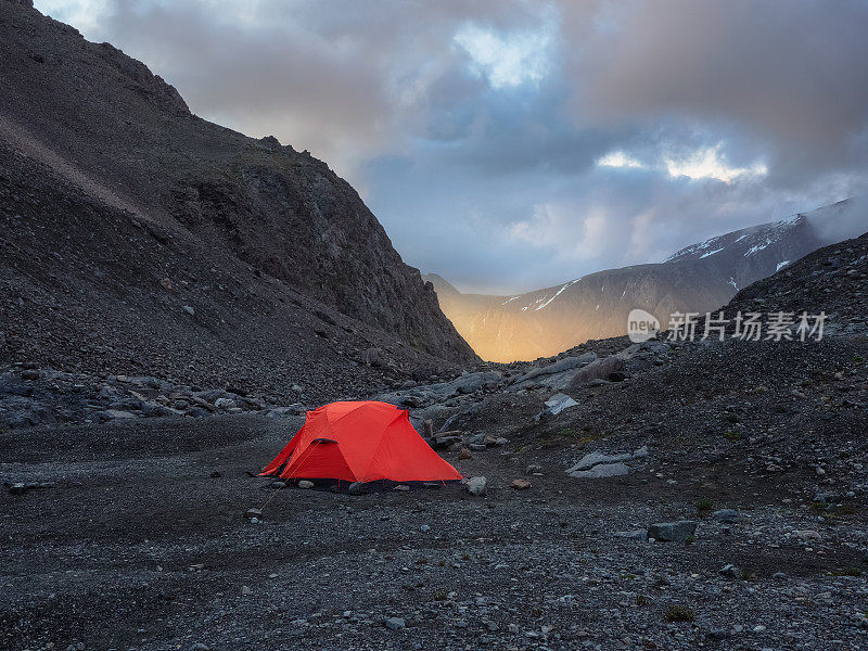 超现实主义高山景观与帐篷在岩石山在日出。美丽的晨山在低云中。在阴天的高原上，超现实的风景和帐篷。