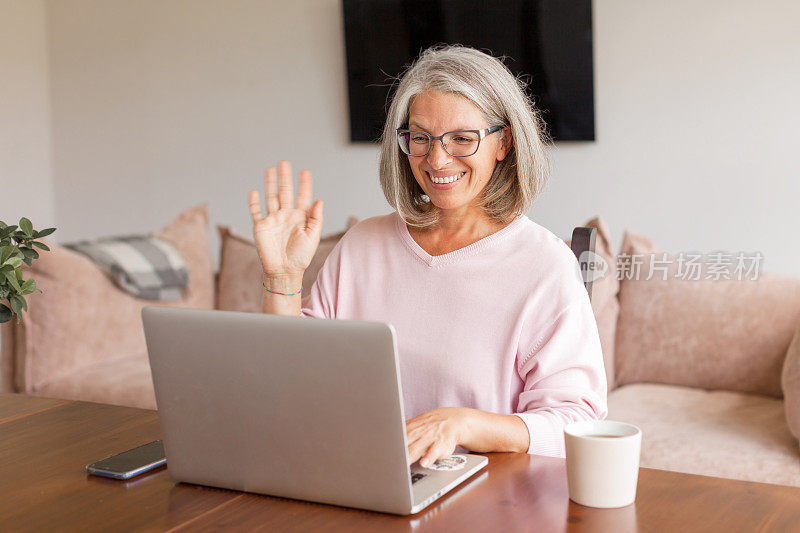 一个快乐的中年妇女正在用笔记本电脑打视频电话