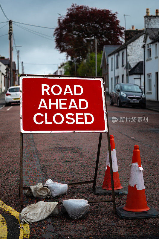 在一个城镇的街道上，亮红色的道路上有一个关闭的标志