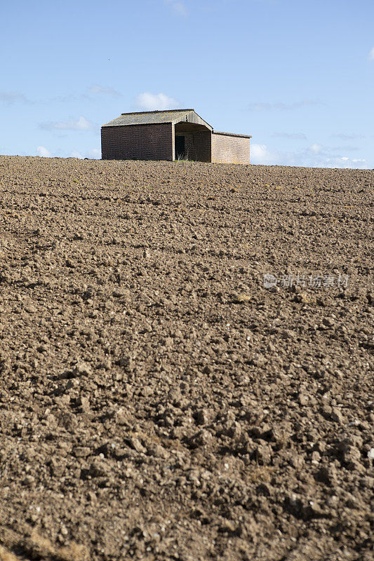 农场建筑在地平线上的耕地与蓝天和复制空间
