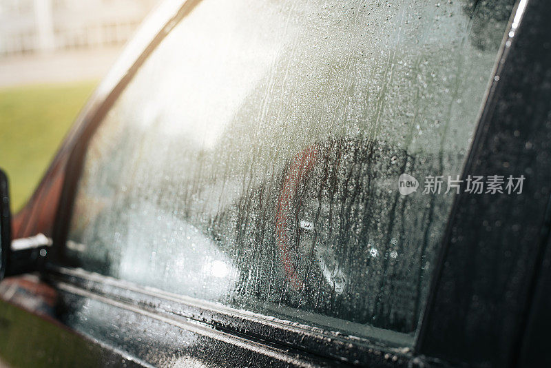 玻璃湿了，雨后的水滴从车窗上流下来。特写，侧视图，选择性软聚焦